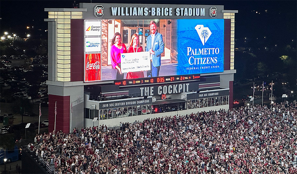 Jumbotron at Williams-Brice Stadium showcasing 'Teacher of the Game' with a crowd in the stands.