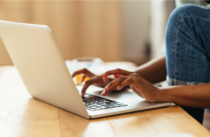 Close-up of hands typing on a laptop keyboard.