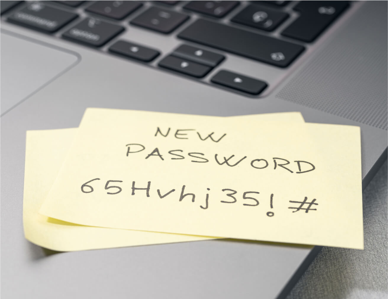 Sticky note with 'NEW PASSWORD' written on it, on a laptop.