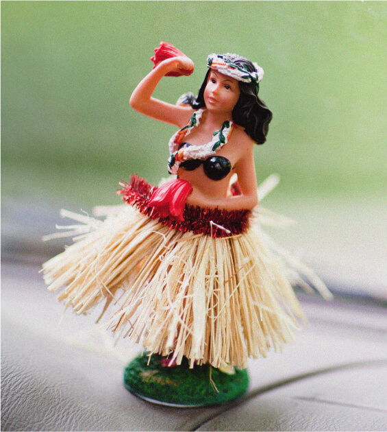 Hula girl dashboard figurine with grass skirt and lei.