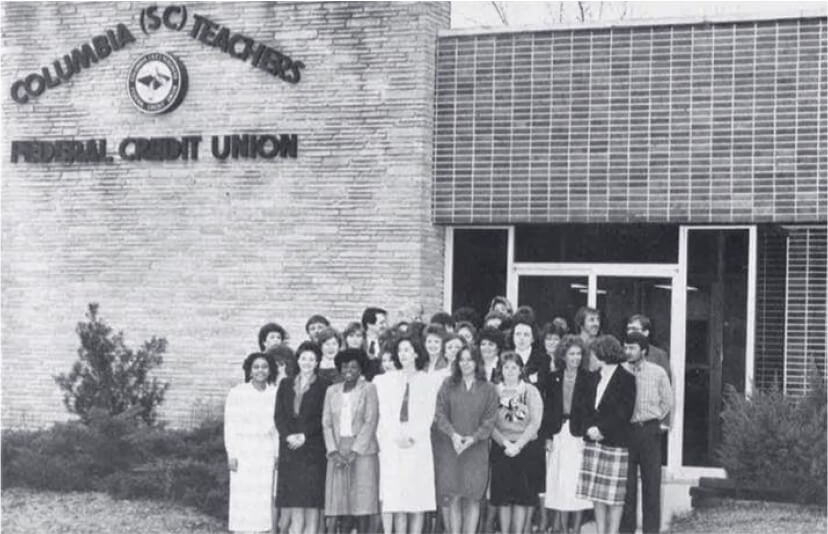 A black and white photo of staff in front of the Columbia Teachers FCU building.