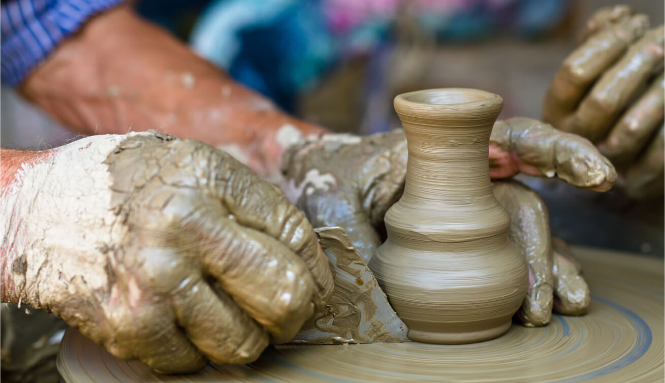 Hands molding clay on a potter's wheel, crafting a vase.