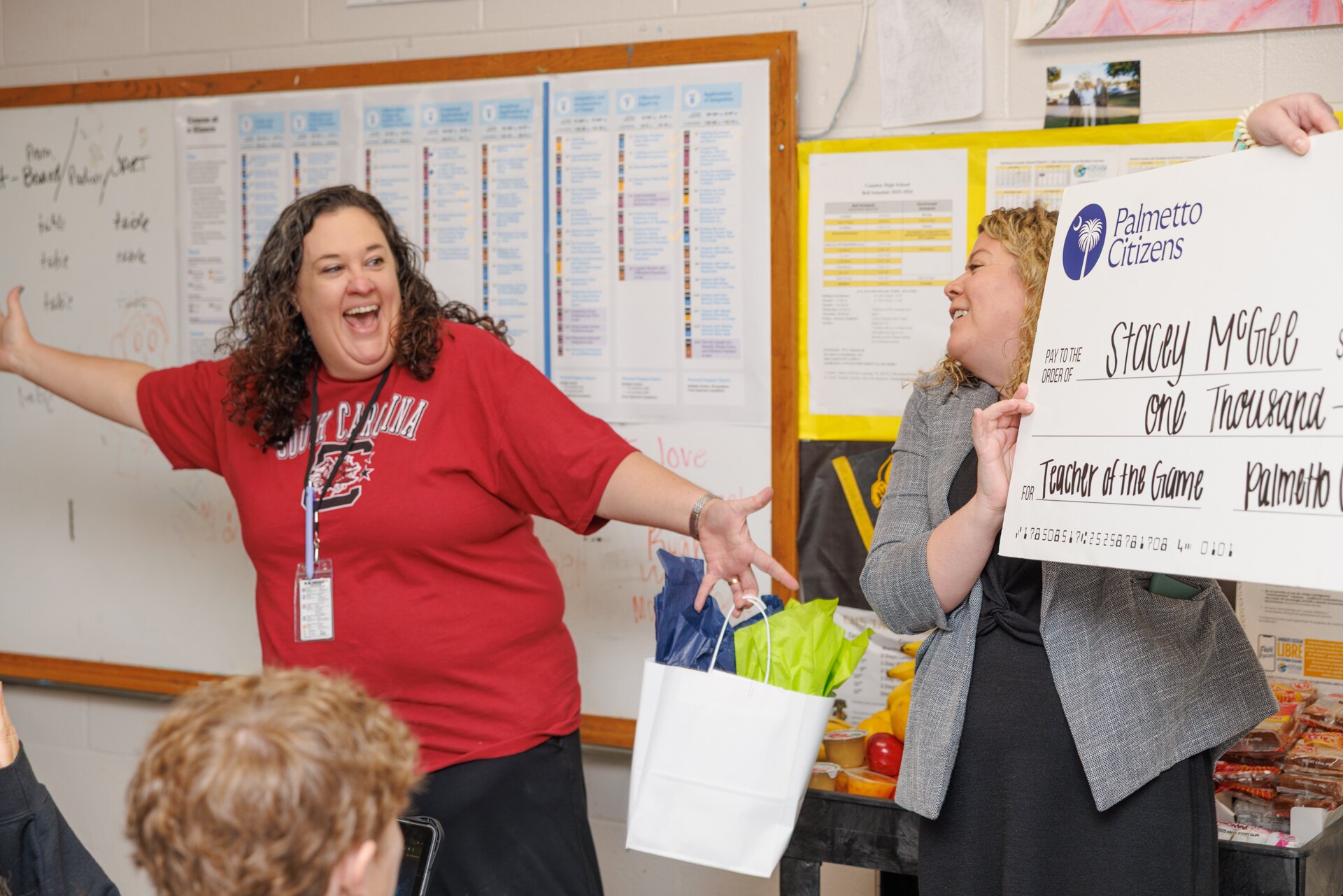 A teacher reacts as a Palmetto Citizens representative presents a $1,000 Teacher of the Game check.