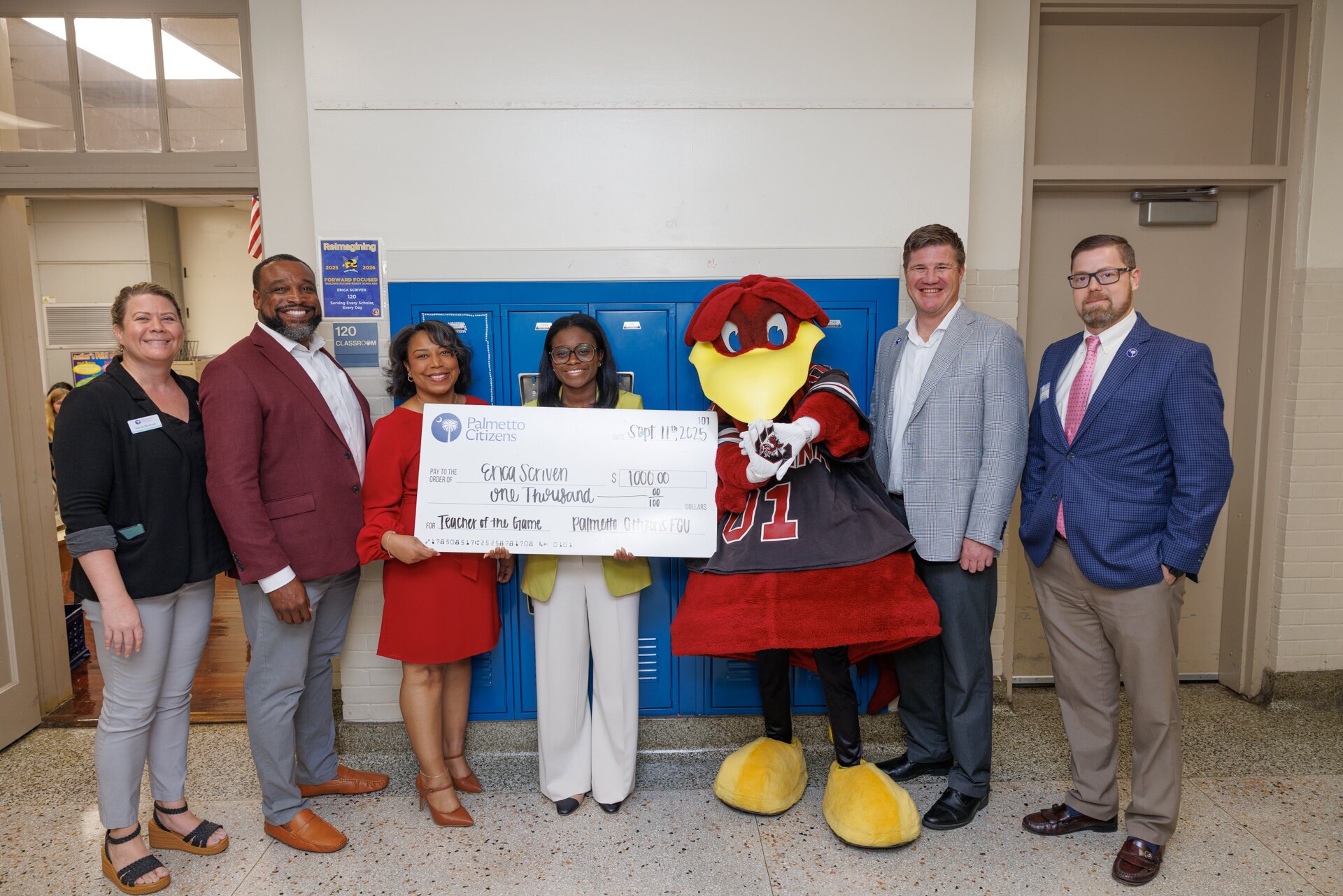 A teacher and school representatives pose with Cocky and a $1,000 Teacher of the Game check.